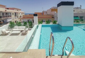 A rooftop pool with a clear blue water feature, surrounded by lounge chairs and a glass balustrade. - LE2C Luxury New build apartment near the beach (Estepona)