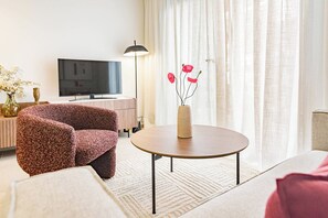A modern living room with a round table, a sofa, a TV, and a lamp. - LE2C Luxury New build apartment near the beach (Estepona)