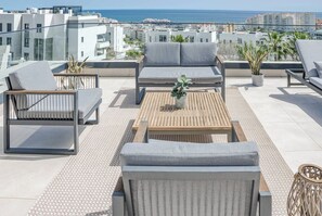 A rooftop terrace with outdoor seating, a wooden table, and potted plants. - LMe103A - Bright modern flat with amazing terrace (Estepona)