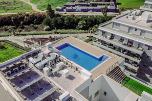 Een zwembad op het dak met een heldere blauwe waterpartij, omgeven door airconditioningsapparaten en een moderne gebouwconstructie.