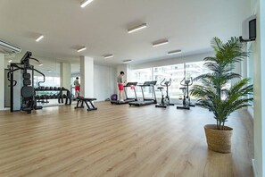 A gym with cardio equipment, weight machines, and a large window providing natural light. - JG- Top modern apartment in Nueva Andalucia (Marbella)