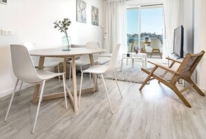 Un comedor moderno con una mesa redonda, sillas blancas y una silla de mimbre.