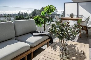 A modern outdoor seating area with a sofa, a table, and potted plants. - Modern Nueva Andalucia Apt, Pool & Gym - JG (Marbella)