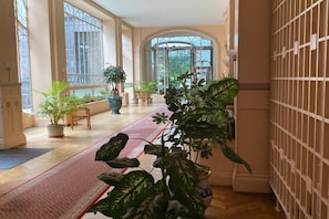 A spacious hallway with large windows, potted plants, and a red carpet. - Town Centre Apartment, Mont-Dore (Mont Dore Puy-De--Dome)
