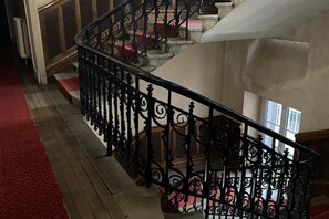 A black wrought iron staircase with a red carpeted landing area. - Town Centre Apartment, Mont-Dore (Mont Dore Puy-De--Dome)