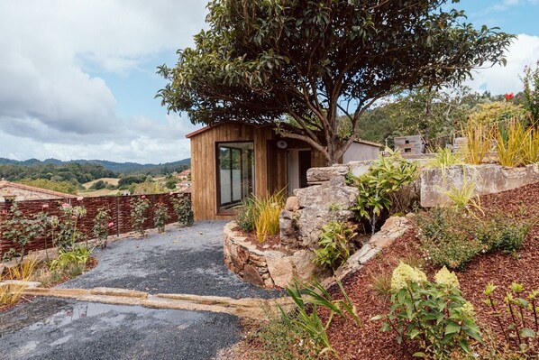 A modern building with a wooden exterior, a glass door entrance, and a stone retaining wall.