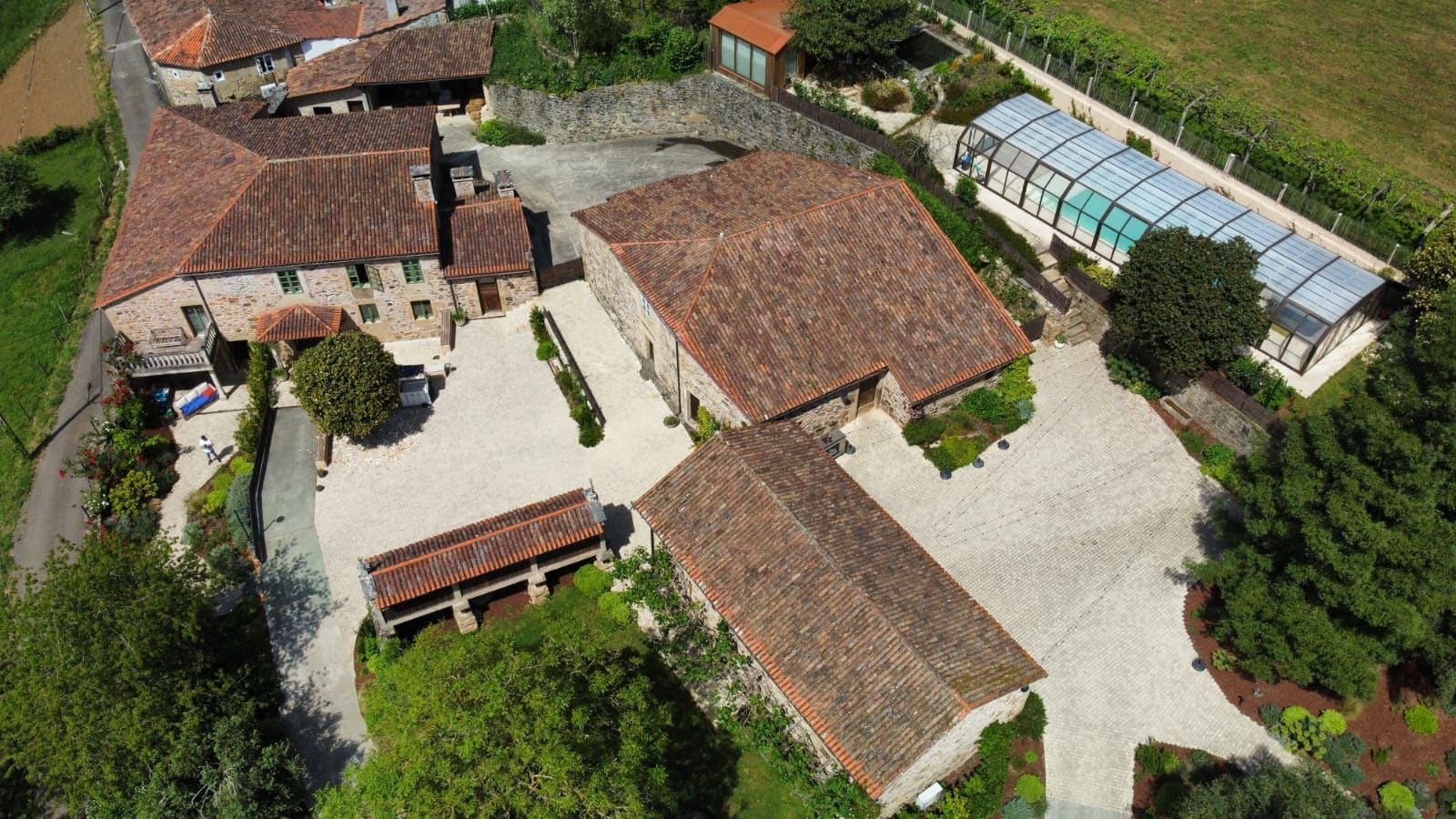 Un patio con varios edificios, un invernadero y una piscina.