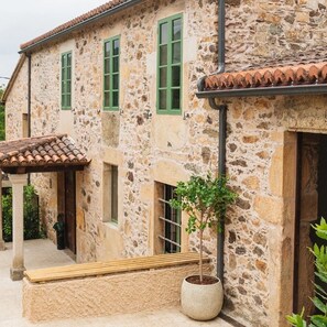 A stone building with green shutters, a tiled roof, and a potted plant. - Vrbo Property (Vila de Cruces)
