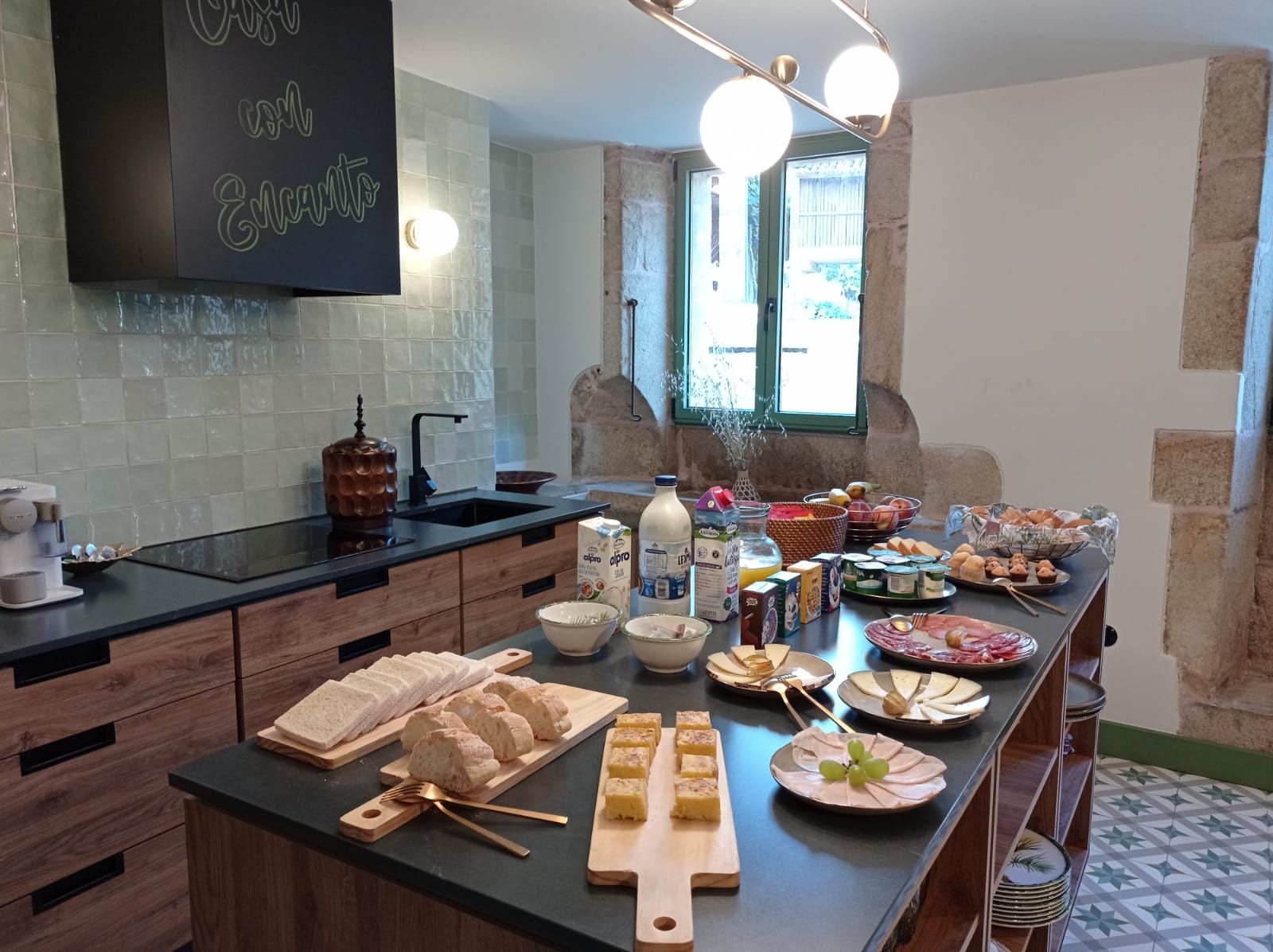 Una cocina con un bufé de desayuno que ofrece pan, bollería, queso y frutas.