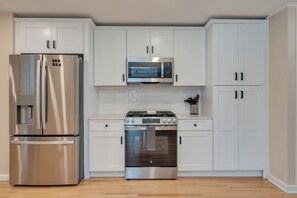 A modern kitchen with white cabinets, a stainless steel refrigerator, a microwave, and an oven. - Huge 7 bedroom house - pool, hot tub, full bar, close to Avalon & Stone Harbor (Middle Township)
