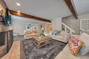 Ein geräumiges Wohnzimmer mit Kamin, zwei Sofas, einem Couchtisch und einer Treppe.