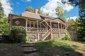 Ein zweistöckiges Haus mit einer Veranda, einem Schornstein und einem Kiesweg, der zum Eingang führt.