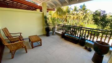 A covered outdoor area with a concrete floor, wooden furniture, and potted plants.