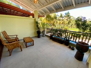 A covered outdoor area with a concrete floor, wooden furniture, and potted plants.