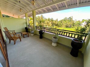 A covered balcony with seating, potted plants, and a view of greenery. - Diyanilla Resort and Wellness (galle)