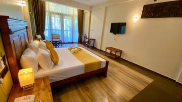 A hotel room with a bed, bedside table, lamp, and a television mounted on the wall.