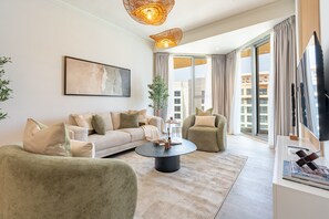 A modern living room with a sofa, armchairs, a coffee table, and a television. - Seaside 2BR & AsstRm w/ Gulf of Oman Views, Minutes from Khorfakkan Waterfalls (Khor Fakkan)
