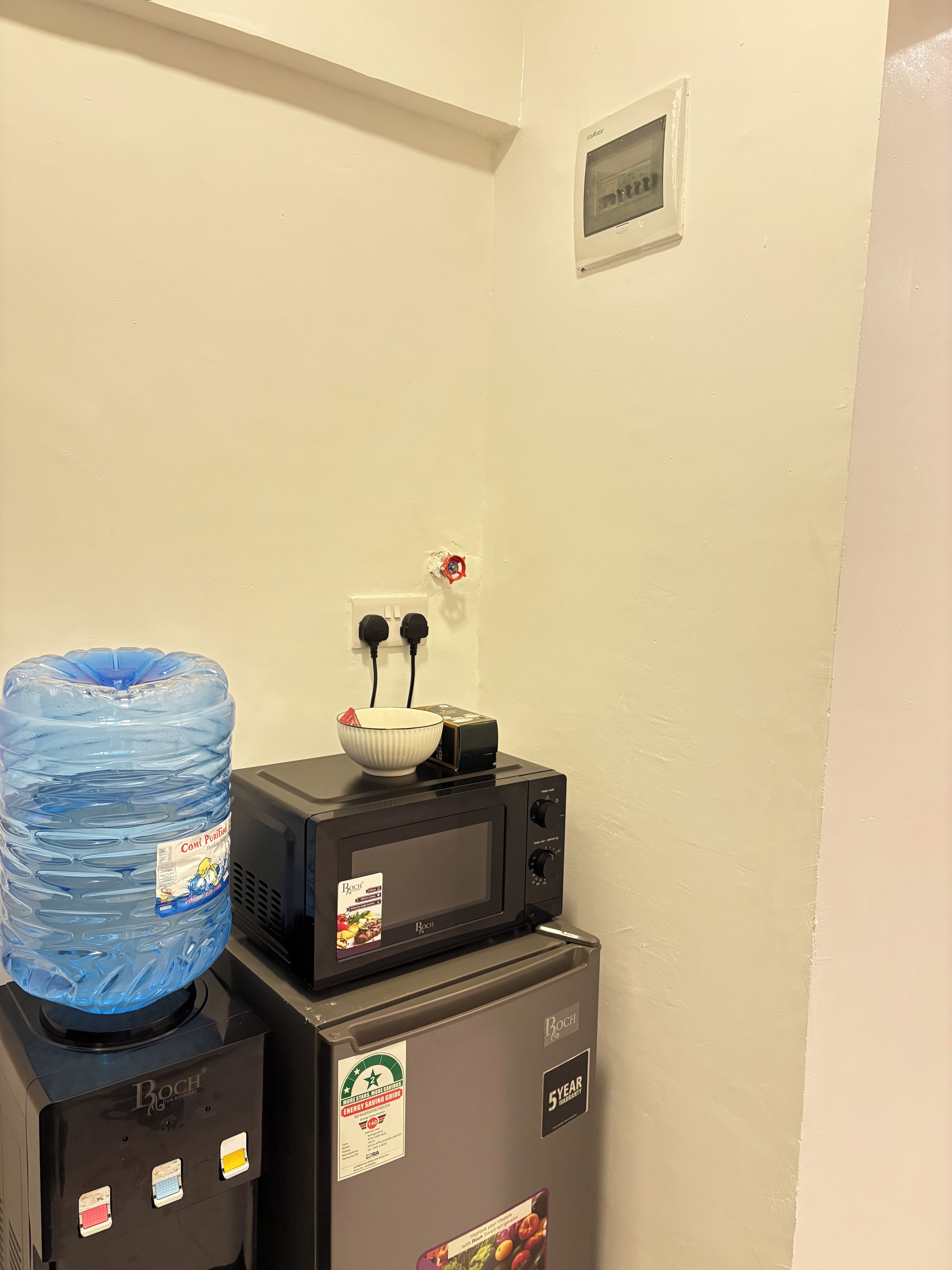 A kitchenette with a Bosch microwave, a water dispenser, and a water jug.