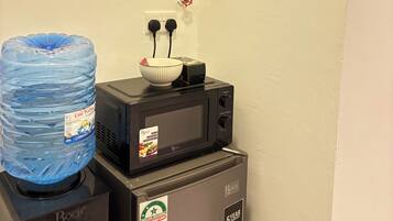A kitchenette with a Bosch microwave, a water dispenser, and a water jug.