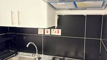 A kitchen with white cabinets, a stainless steel sink, a gas stove, and a black tiled backsplash.