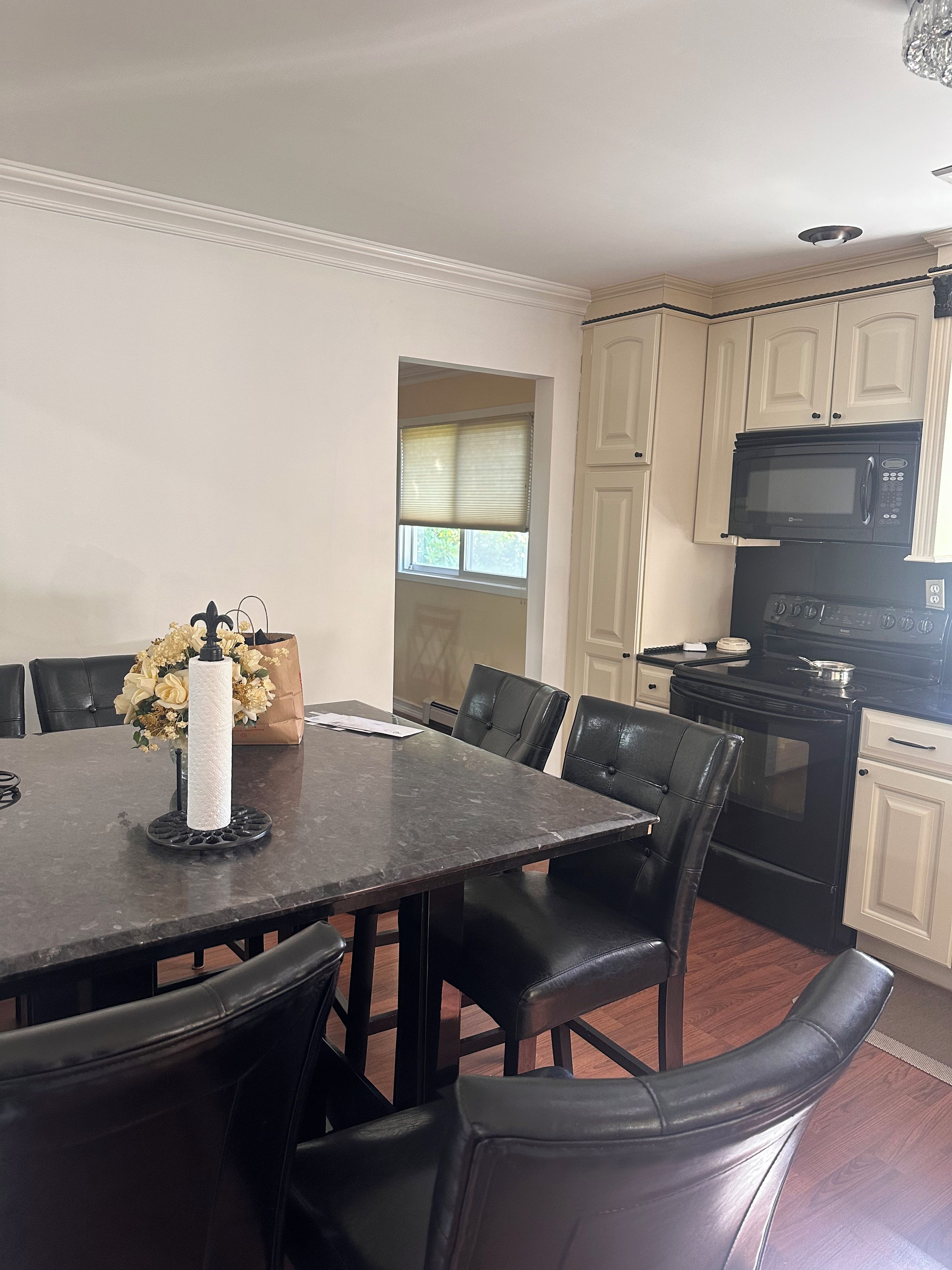 A dining area with a table, chairs, and a vase with flowers.