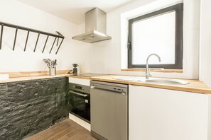 Una cocina moderna con lavavajillas, estufa y una ventana sobre el fregadero.