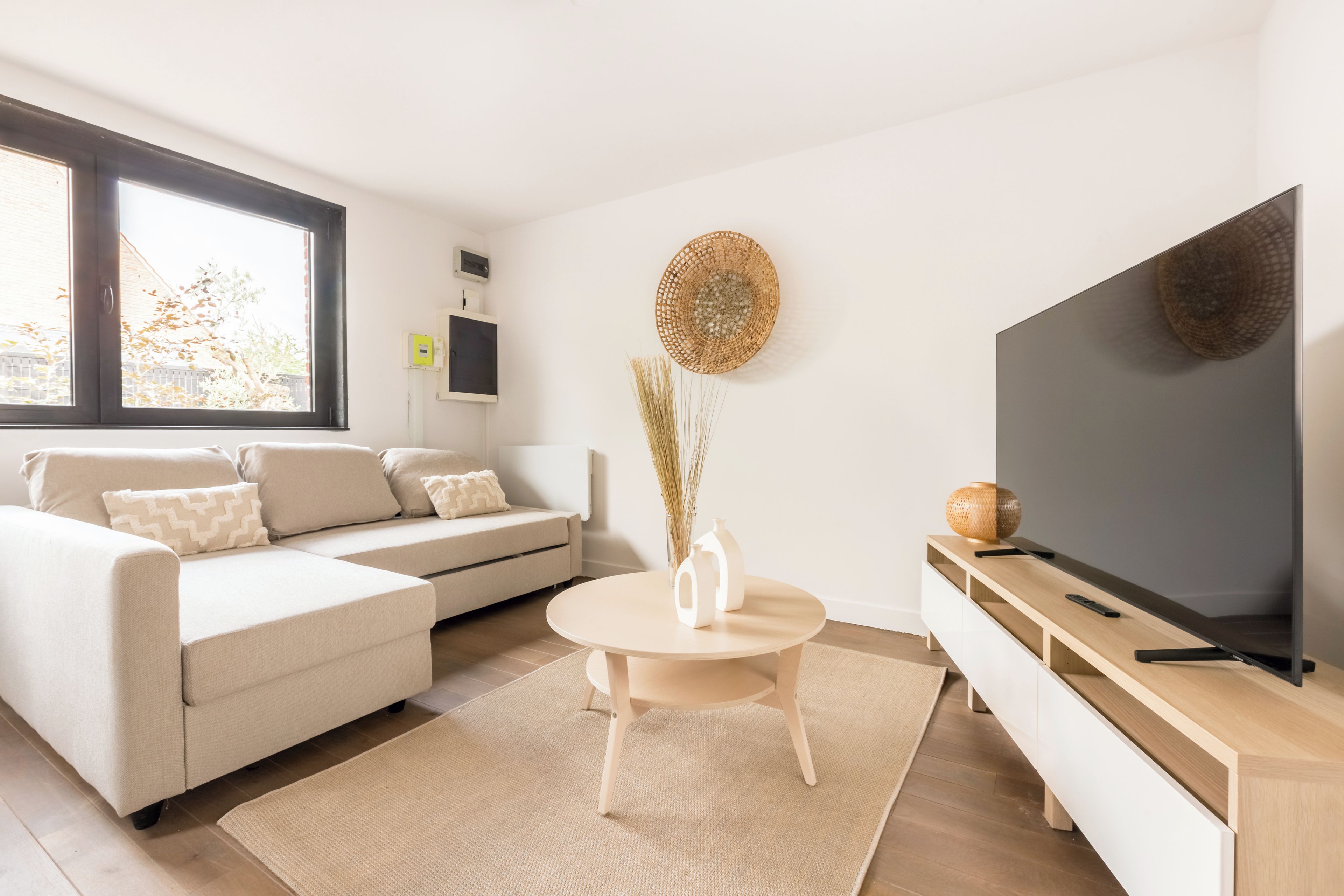 A modern living room with a sofa, a round coffee table, a TV, and a decorative wall piece.