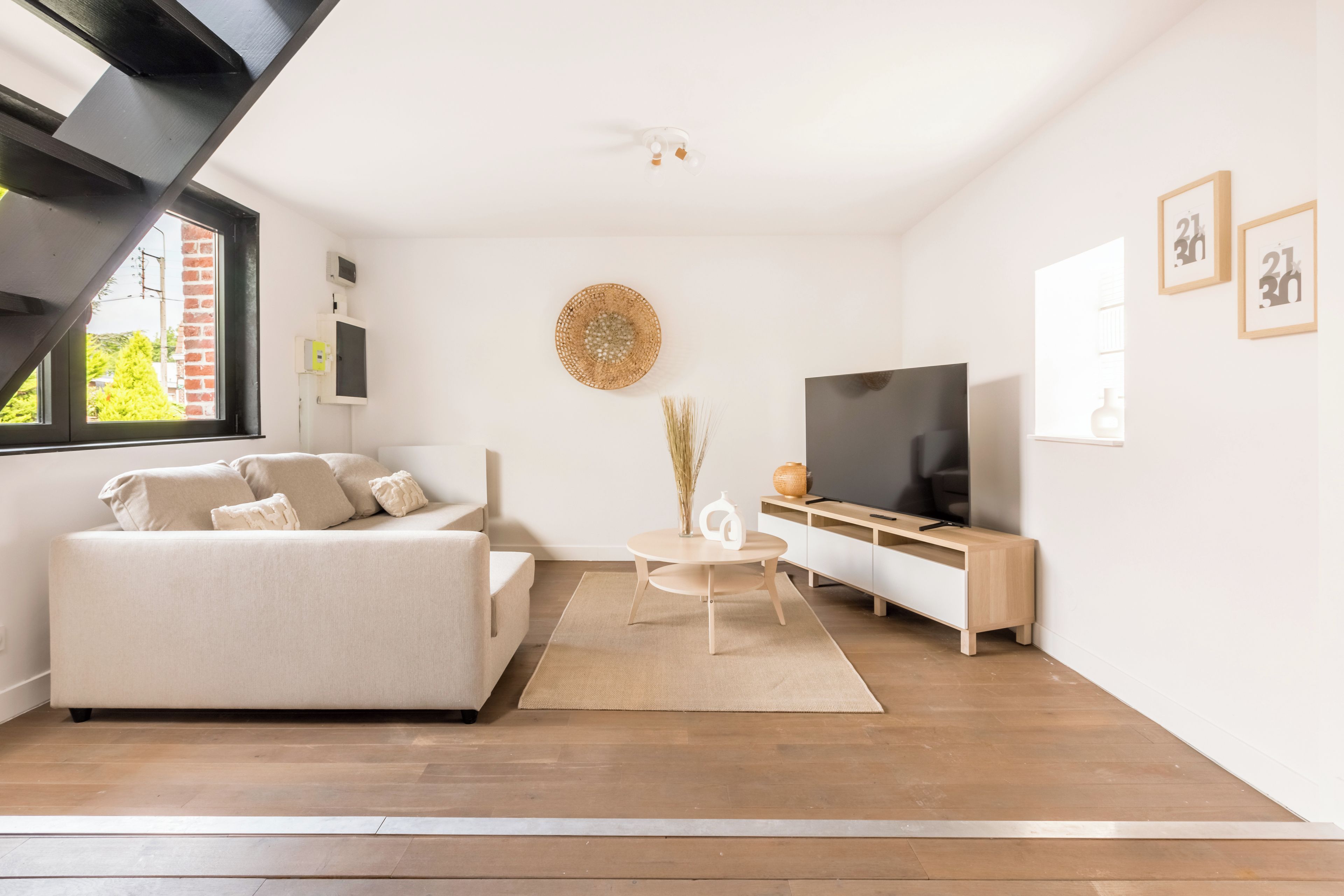 Een moderne woonkamer met een bank, televisie en een klein tafeltje.