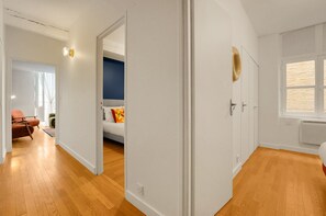 A modern apartment with a wooden floor, a bed with colorful pillows, a sofa, and a dining area. - L'Orfèvre - A deux pas de la Place du Capitole (Toulouse)