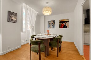 A dining room with a round table set for six, surrounded by six green upholstered chairs. - L'Orfèvre - A deux pas de la Place du Capitole (Toulouse)