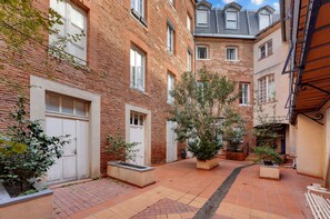 Un cortile con edifici in mattoni, piante in vaso e pavimento piastrellato.