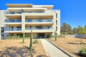 A multi-story residential building with balconies, a paved entrance area, and a landscaped garden. - Les Jardins de Vignola - Proche du Port (Porto-Vecchio)