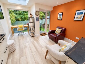 A modern living room with a leather sofa, a dining table with yellow chairs, and a large window with a view of greenery. - Gore Park House - Victorian Charm & Modern Comfort (Eastbourne)