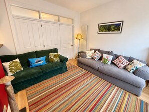 Uma sala de estar com dois sofás, um tapete listrado e um quadro pendurado na parede.