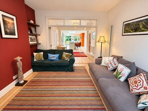 Ein Wohnzimmer mit einem dunkelgrünen Sofa, einem gestreiften Teppich und einem grauen Sofa mit gemusterten Kissen.
