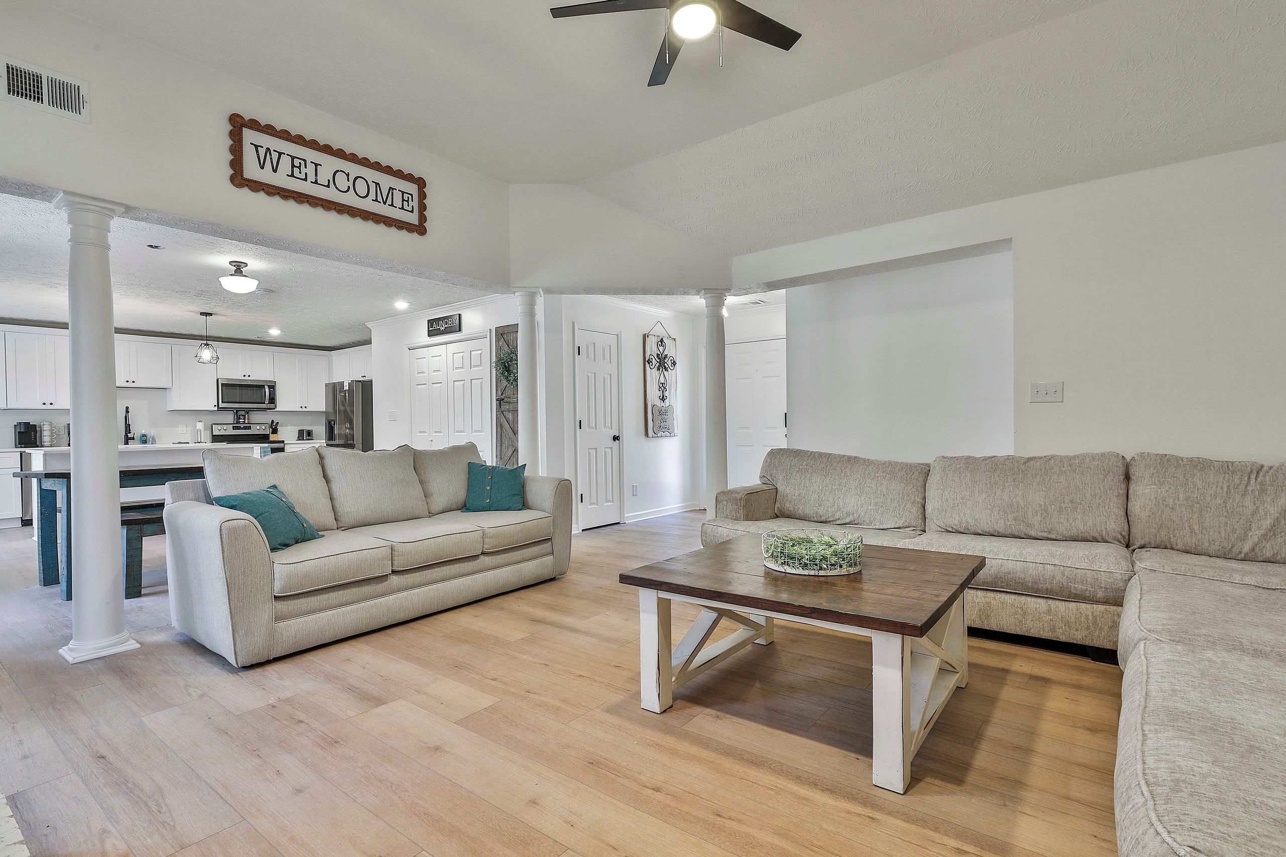 A spacious living area with a sofa, a coffee table, and a kitchen in the background.