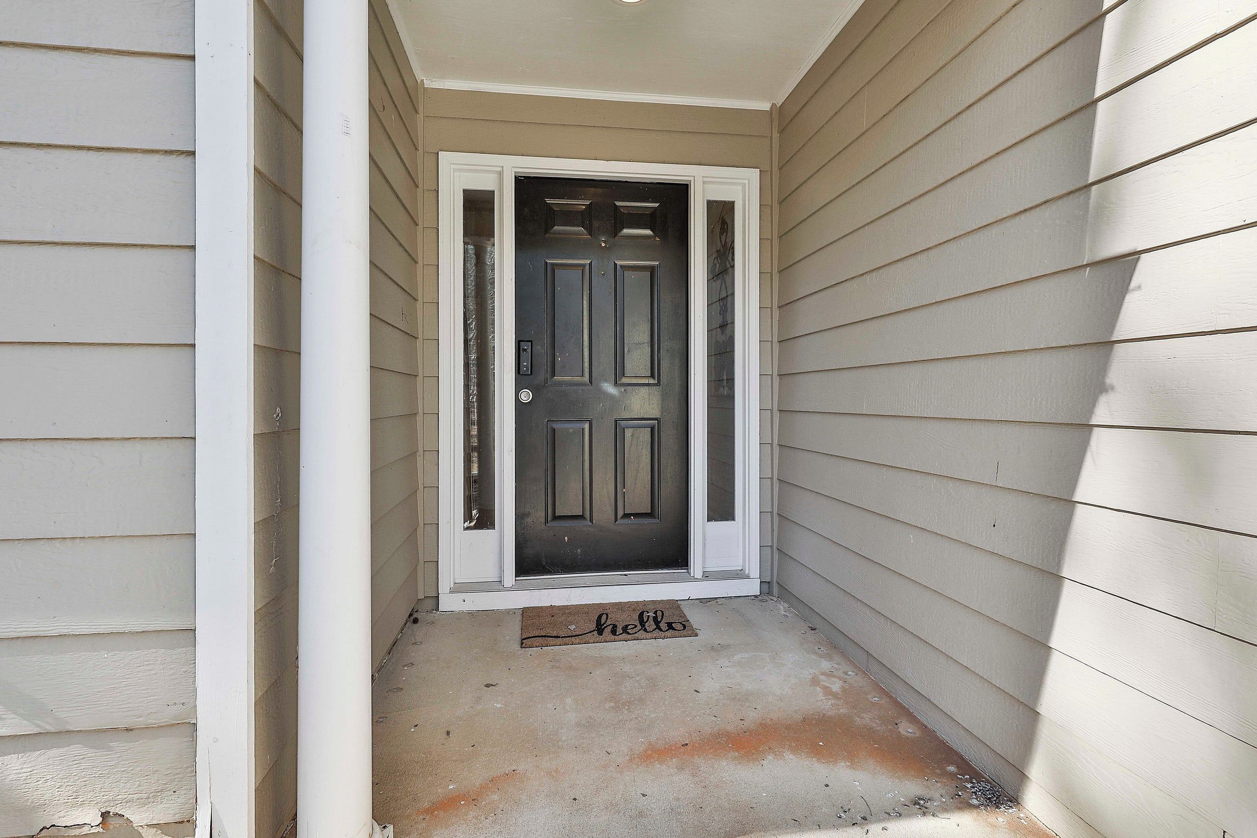 A narrow entryway with a closed door and a doormat.