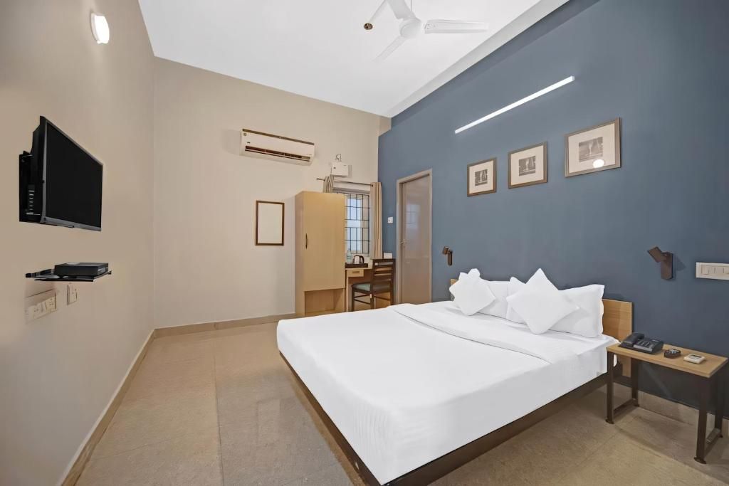 Une chambre d’hôtel équipée d’un lit, d’une table de chevet, d’une télévision et d’un bureau avec une chaise.