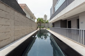A swimming pool with a geometric wall design, surrounded by modern buildings. - Brooklyn by Bhomy (São Paulo)