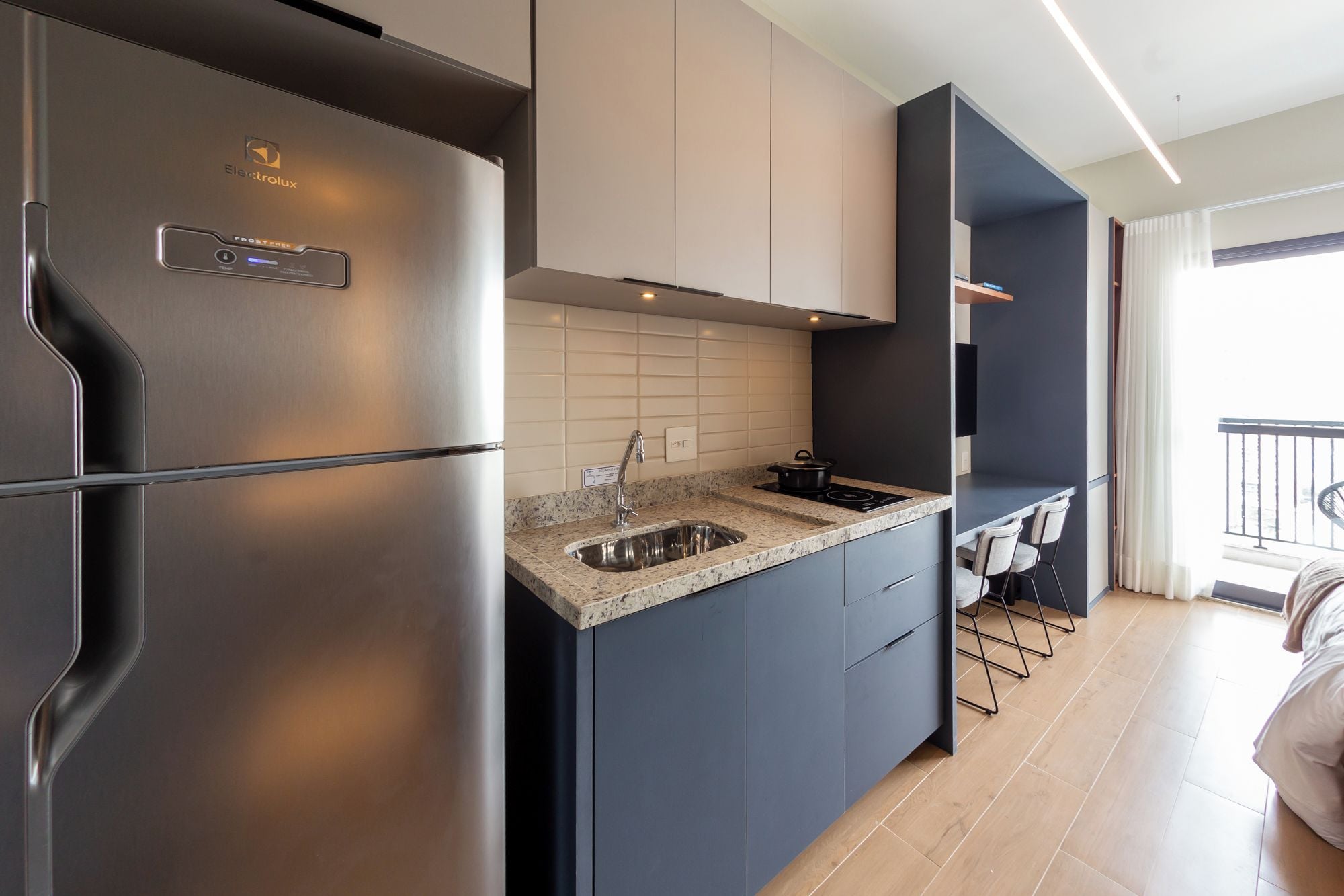 A modern kitchen with a stainless steel refrigerator, a granite countertop, and a built-in stove.