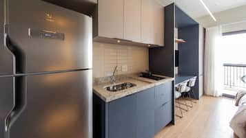 A modern kitchen with a stainless steel refrigerator, a granite countertop, and a built-in stove.