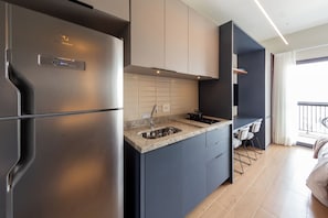 A modern kitchen with a stainless steel refrigerator, a granite countertop, and a built-in stove. - Brooklyn by Bhomy (São Paulo)