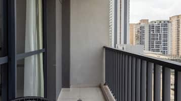 A balcony with a metal railing, a chair, and a view of surrounding buildings.