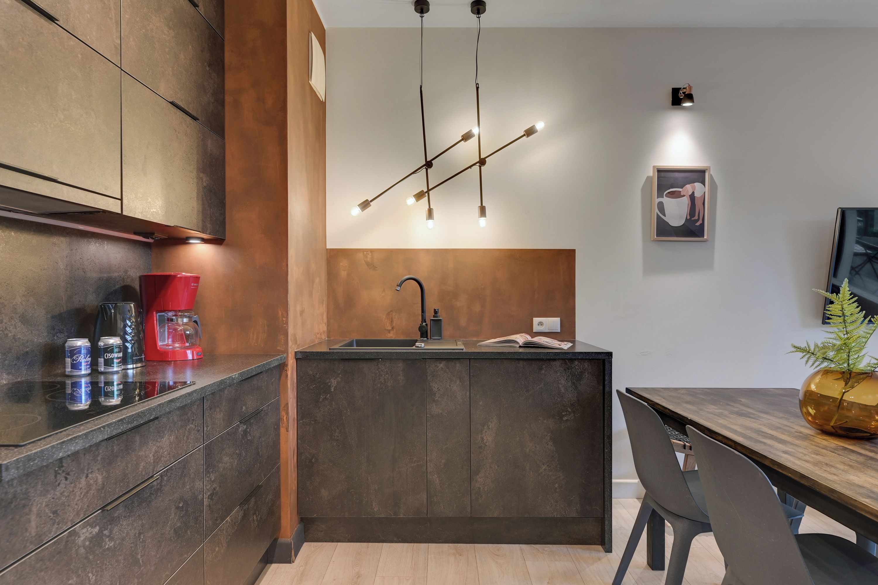 Una cocina moderna con una isla central, cafetera y comedor con mesa y sillas.