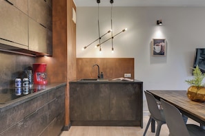 Una cocina moderna con una isla central, cafetera y comedor con mesa y sillas.
