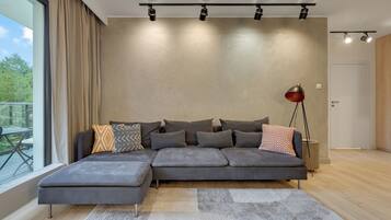 Una sala de estar moderna con un sofá modular, una lámpara de pie y un ventanal con cortinas.