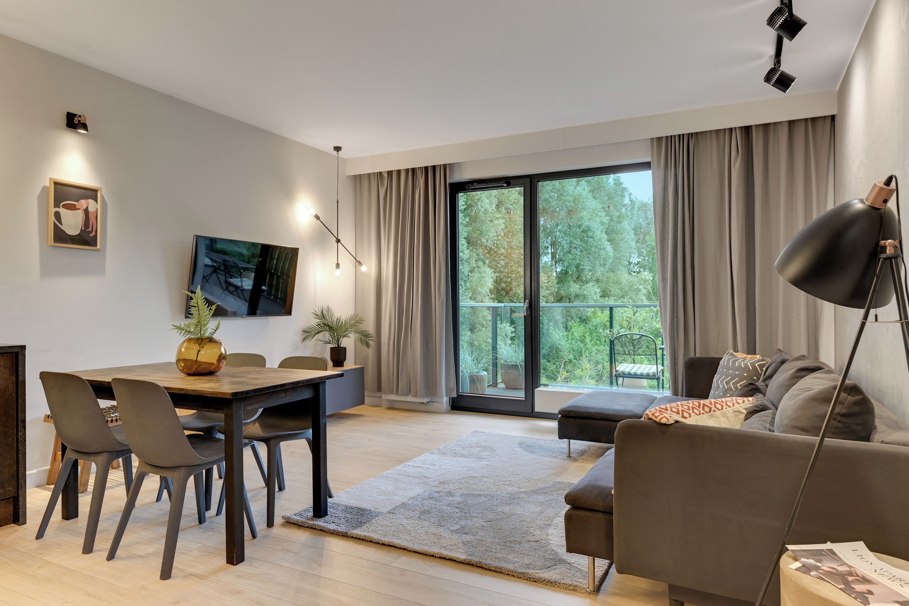 Una sala moderna con comedor, ventanas amplias y vista a zonas verdes.