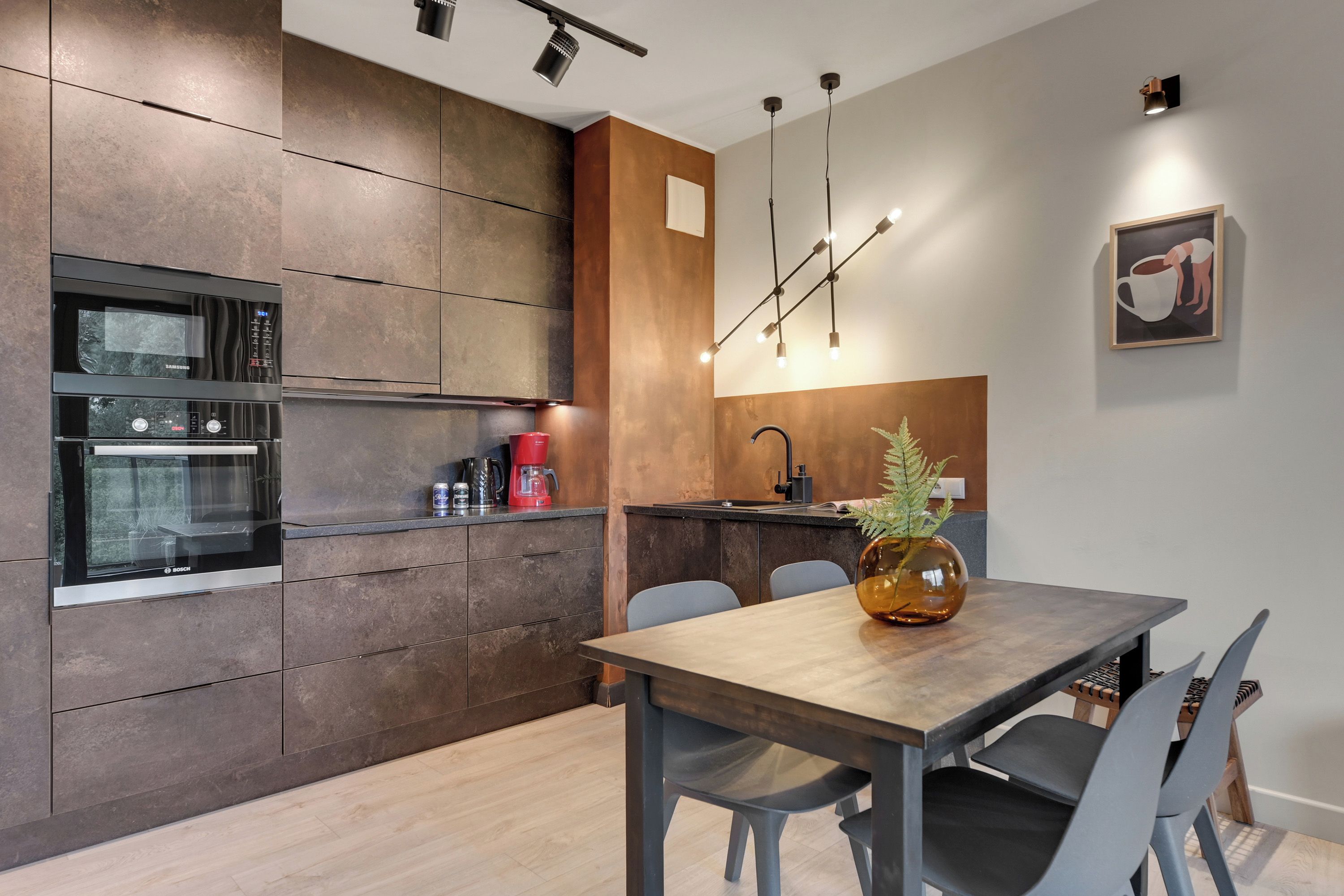 A modern kitchen with built-in appliances, a dining area with a wooden table, and a minimalist decor.