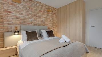 Un dormitorio moderno con pared de ladrillo, cabecero de madera y puerta blanca.