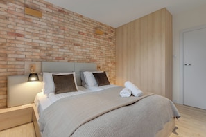 Un dormitorio moderno con pared de ladrillo, cabecero de madera y puerta blanca.